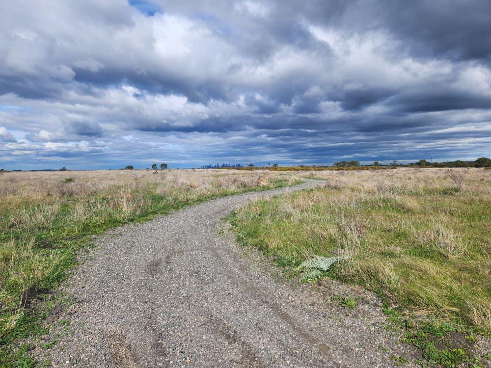 The Eastern Track has a rough gravel surface and curves through grassland.