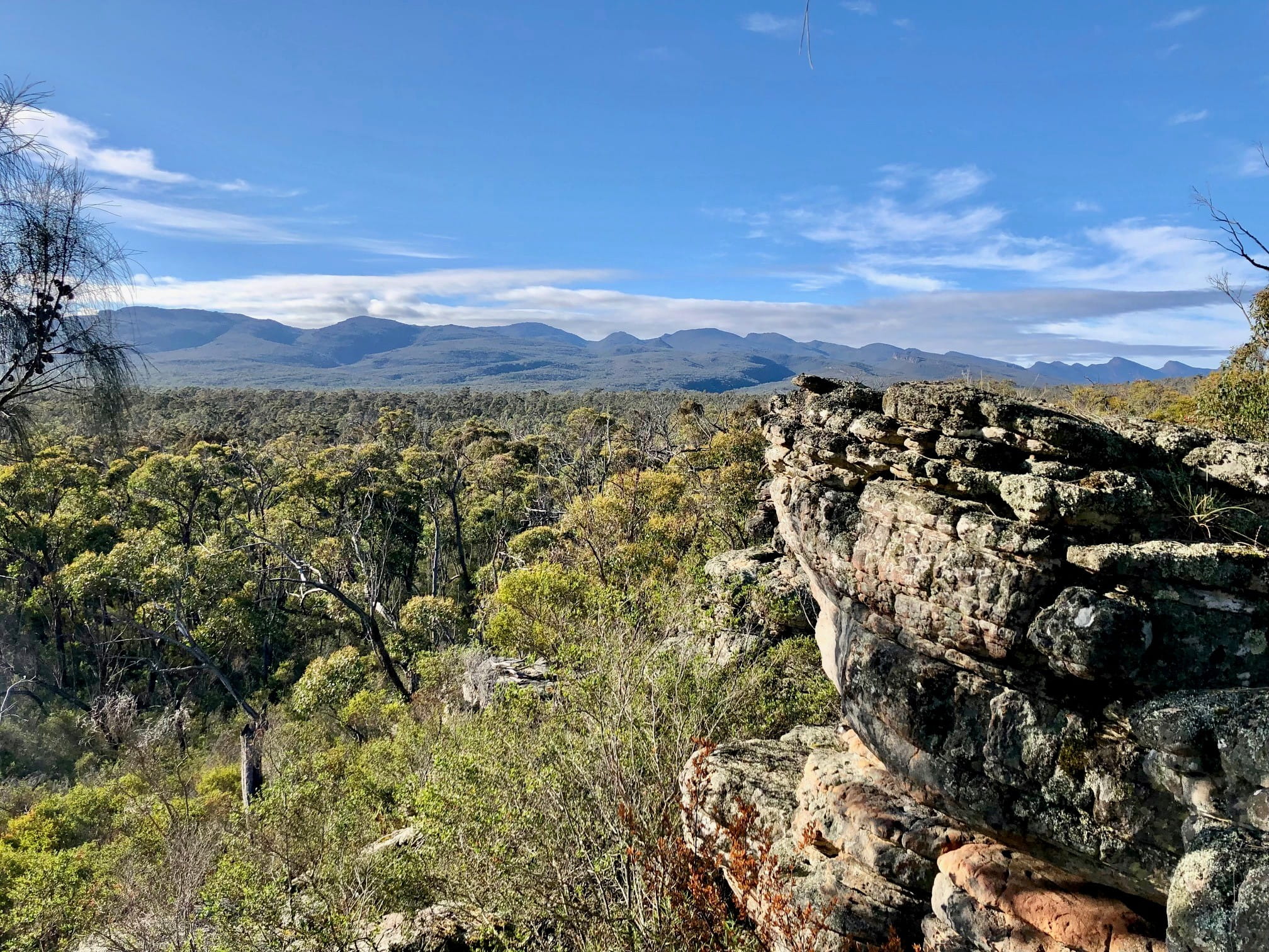 Rocky outcrop with mountains and blue sky in the background