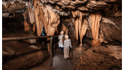 Two children walking through a cave at Buchan Caves Reserve, looking up at stalactites