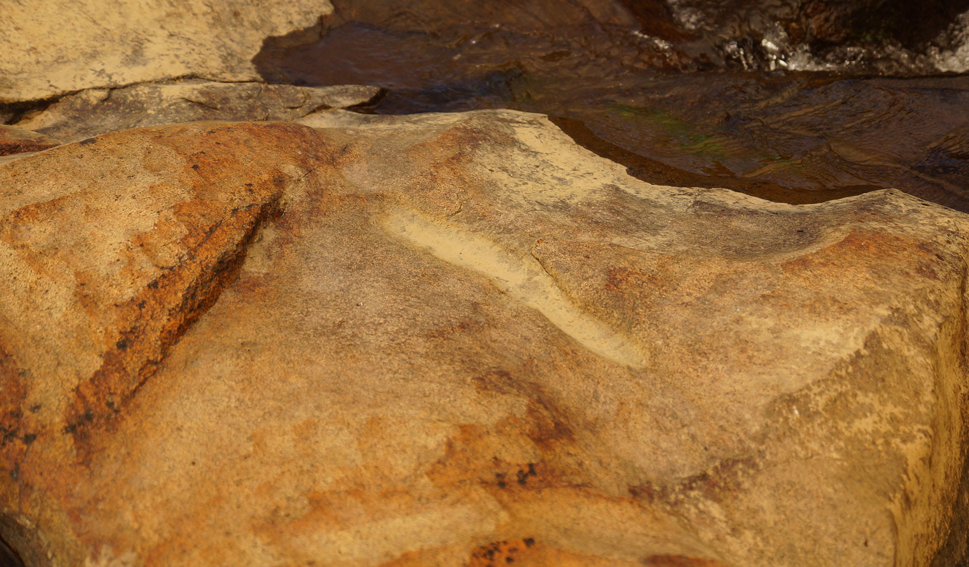 A rocky outcrop with a distinct line carved into the surface.