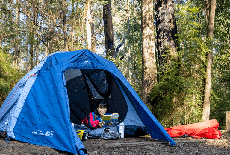 A girl is camping inside of her tent