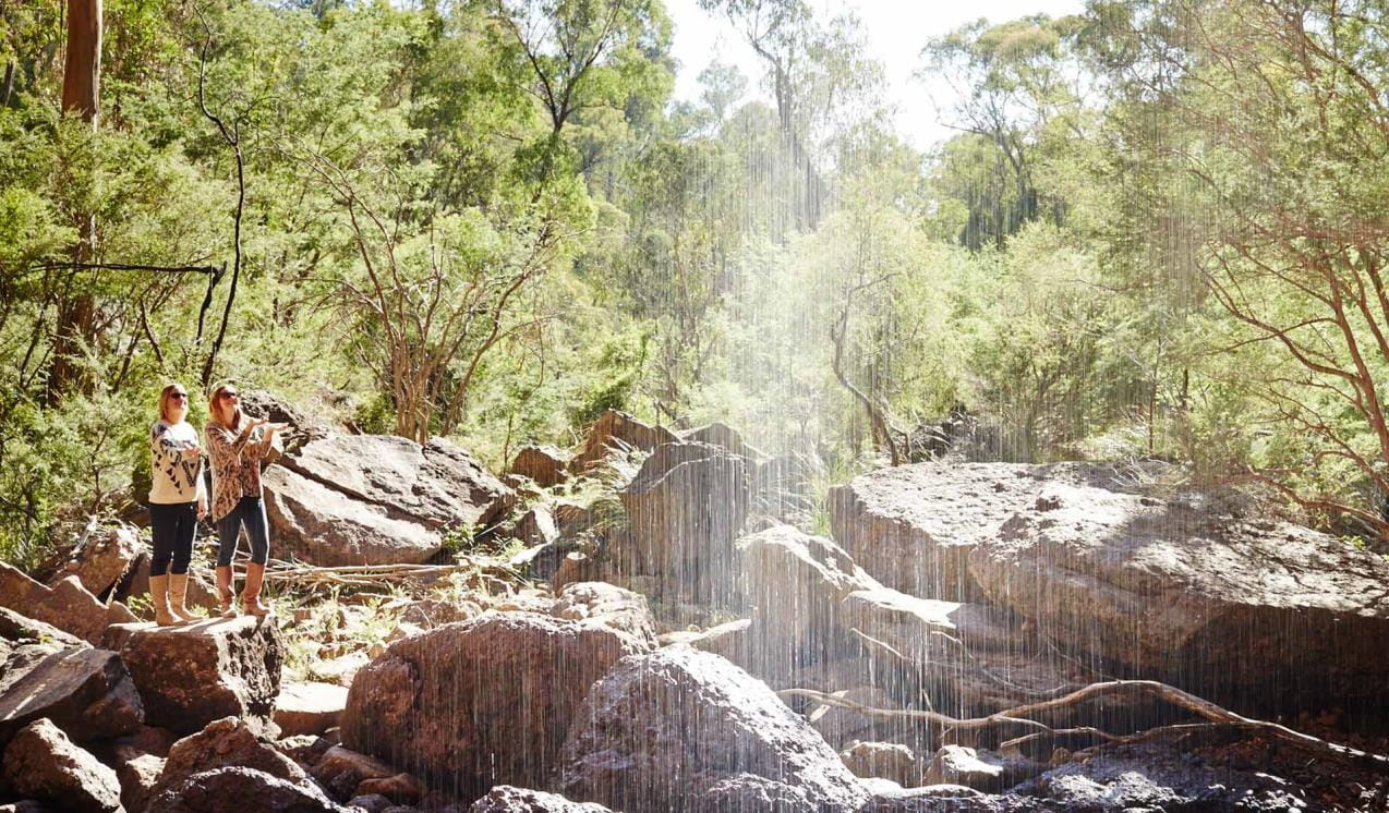 Two women take a photo of the ephemeral Bluff Falls.