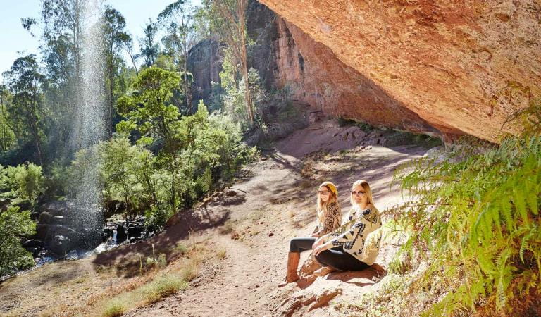 Two women sit beside the ephemeral Paradise Falls located near the headwaters of the King River in the Alpine National Park.