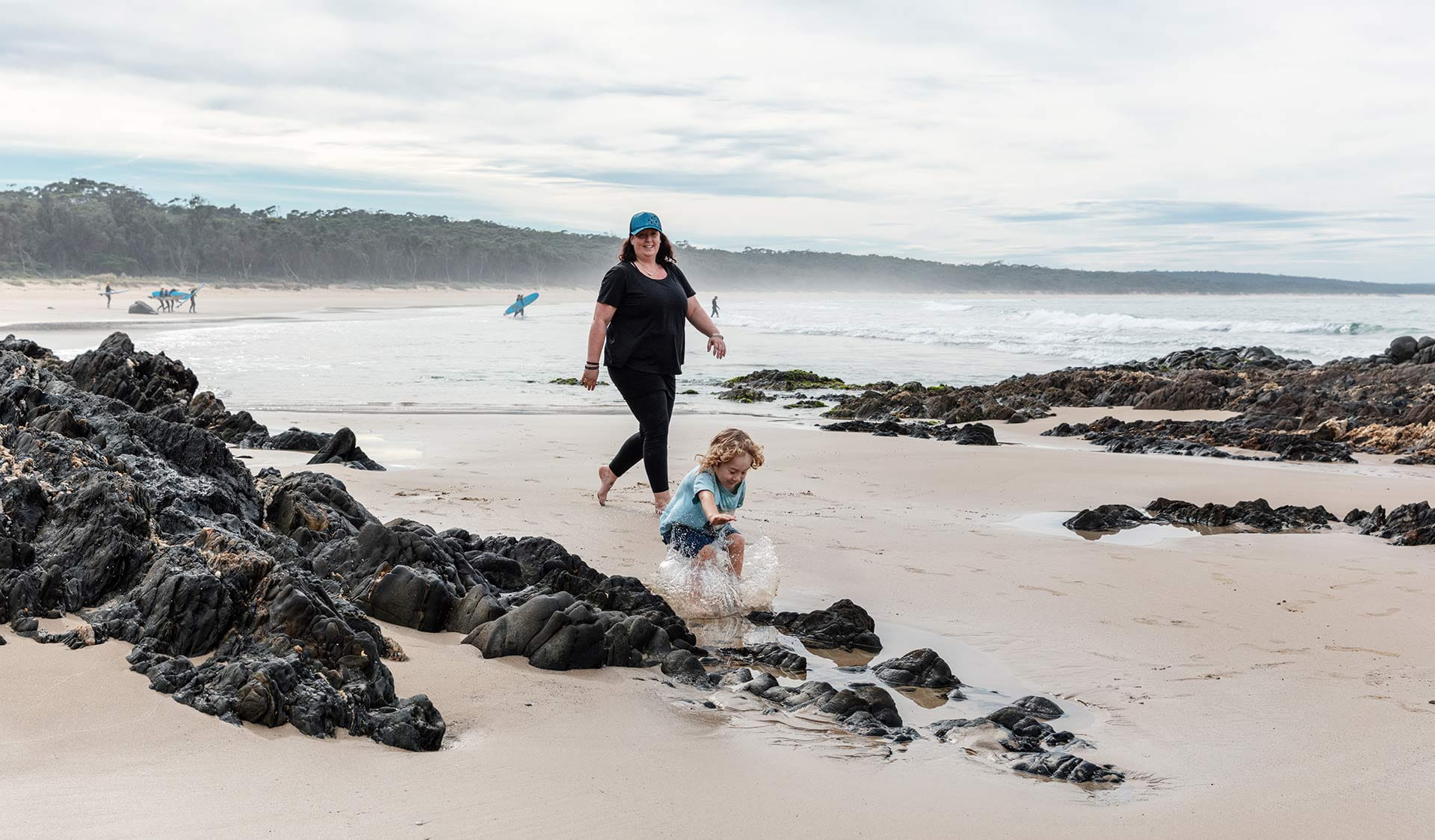 A mother and young son play on the beach at East Cape Beach.