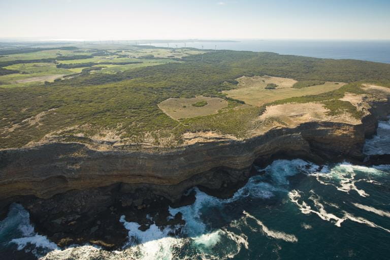 An aerial view of a rocky coastline with deep blue water.