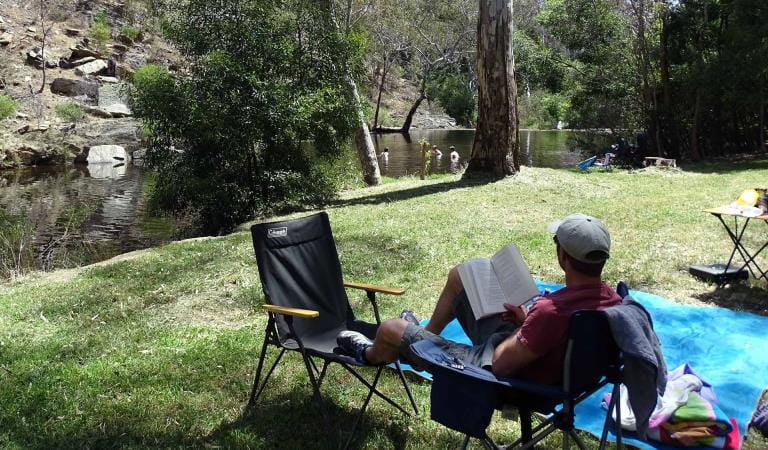 A man watches his children swim in the Loddon River from his campsite at Vaughan Springs.