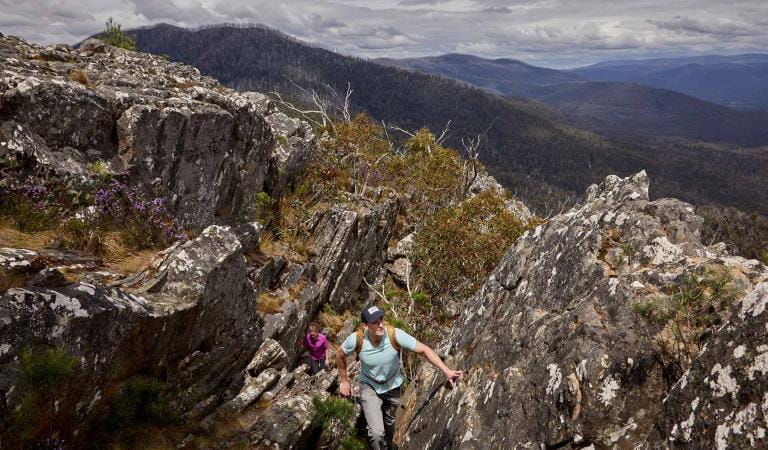 A man leading a woman up through rocky terrain at Canyon Track