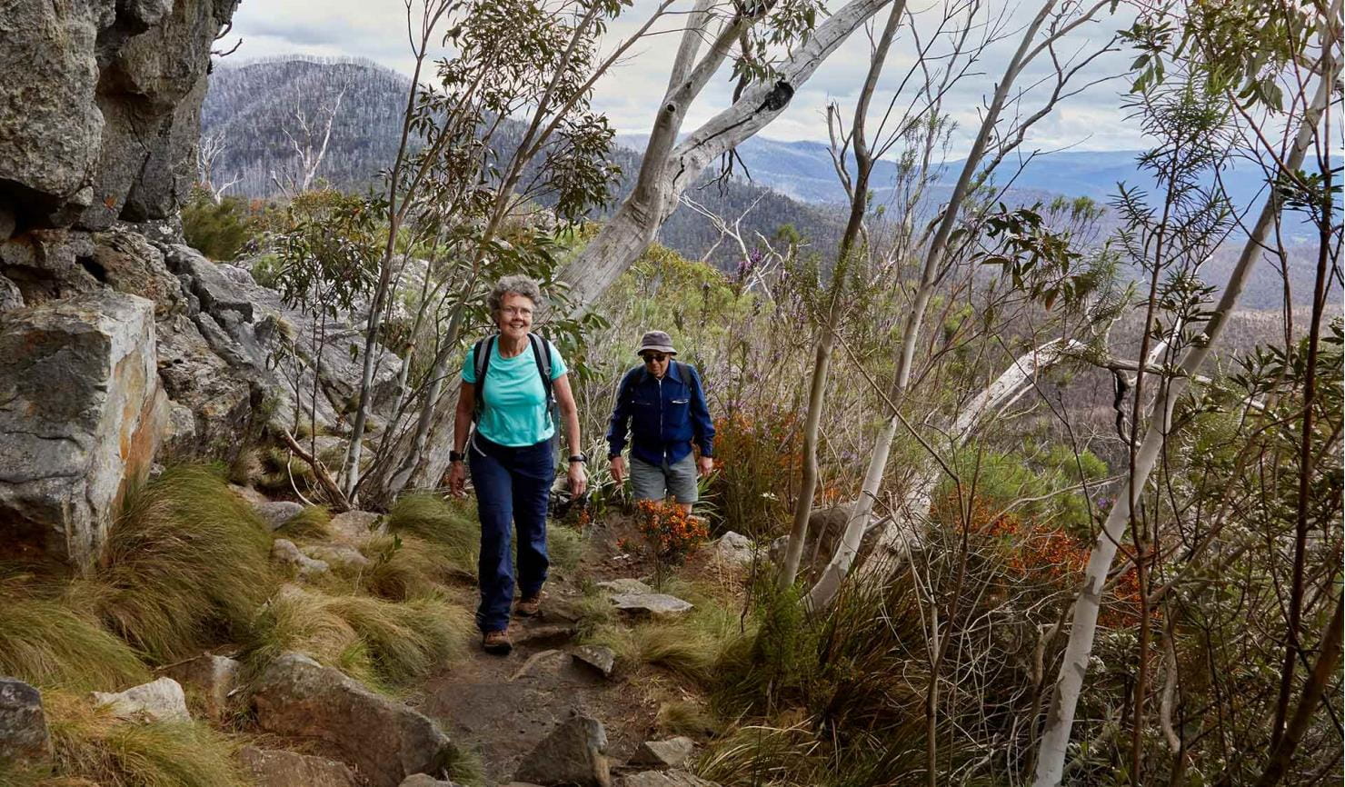 An elderly woman leads her husband along a walking track at Cathedral Range State Park