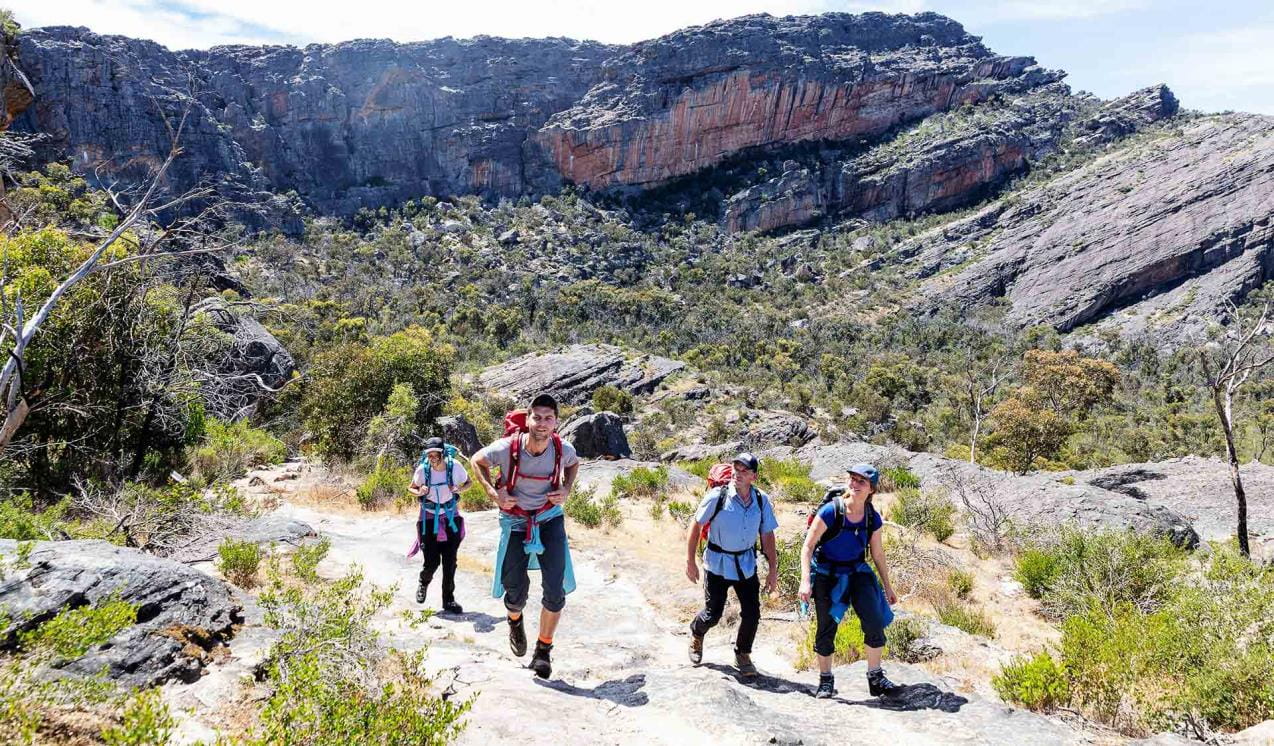 Four friends looking up at the surrounding scenery during their hike at Mount Stapylton