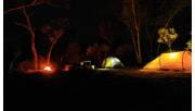 Three tents and a campfire at night time. 