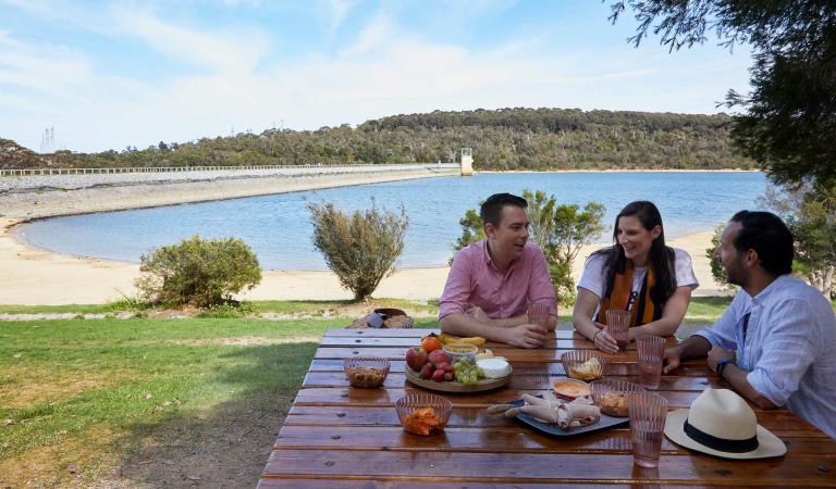 Three friends share a picnic on the shores of Lysterfield Lake.