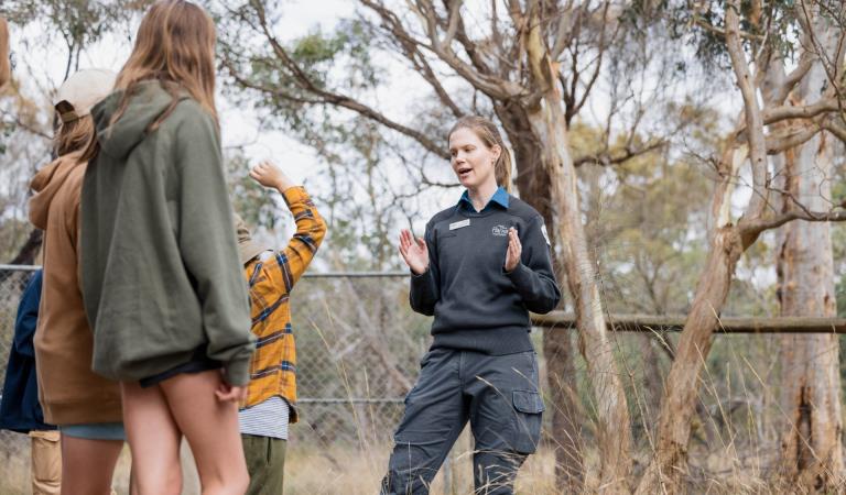 Ranger demonstrating with her hands to group of junior rangers