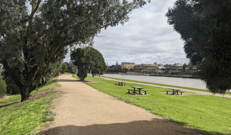 A walking path and picnic tables along the river at Patterson River