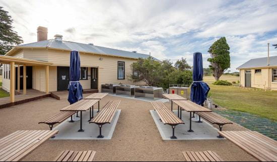 A bbq area with several tables in a coastal landscape.