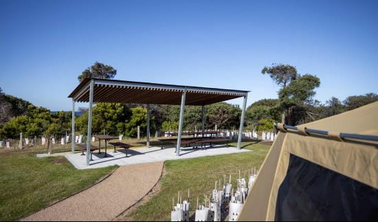 Picnic tables under shelter in a coastal landscape.