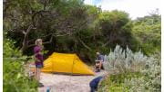 A man and women set up their tent amid the sand dunes at Oberon Bay Campground on the Southern Circuit hiking trail at Wilsons Promontory National Park