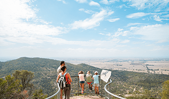 A family looks over You Yangs Regional Park from a lookout