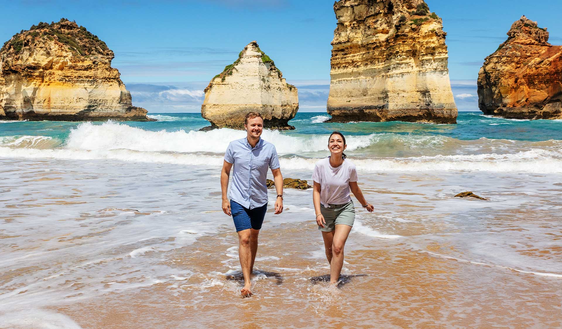 A couple walks in the shallows at the Bay of Islands Coastal Park.