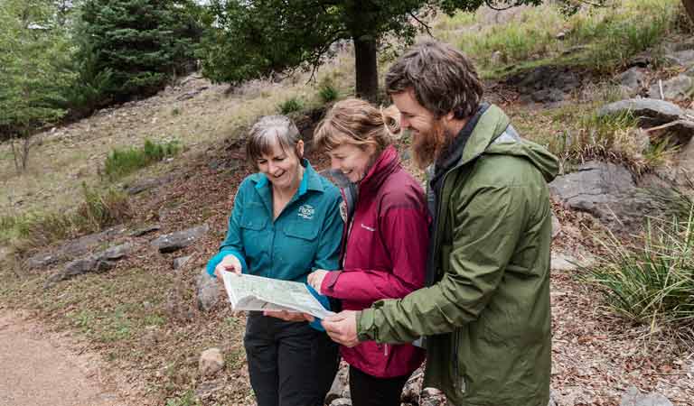 A ranger explains a map to two visitors
