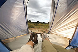 The view from inside a tent, looking out to the grassy landscape and cloudy sky.