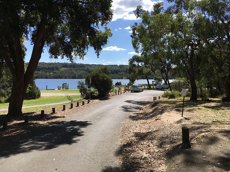 Jetty in the background and path alongside lake at Lysterfield Park.