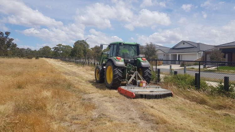 Tractor grass slashing near houses 