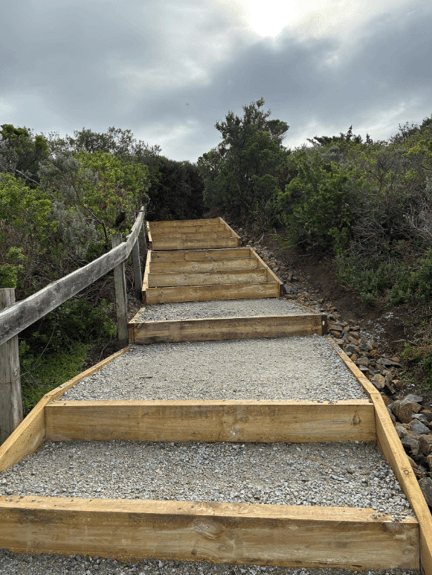 A gravel staircase with a wooden frame on a hilly landscape. 