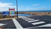 Boat ramp with signage and roadway in the foreground and breakwater in the background