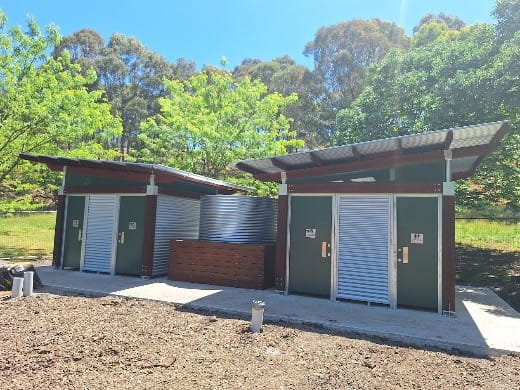 Hawkstowe toilet block under construction.  Toilet areas on each side of the building with a water tank in the middle\.  Concrete path the entire way around the front and sides of the building