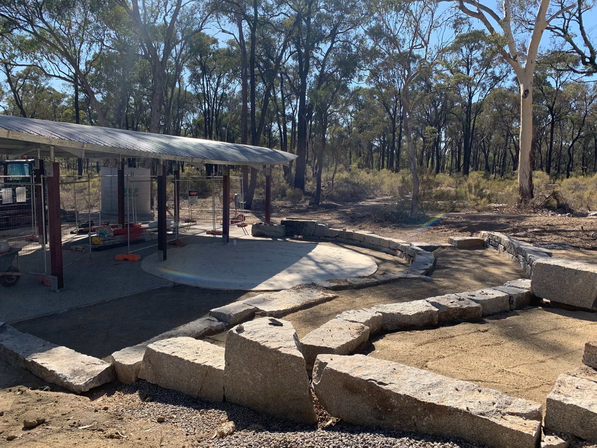 Partially constructed stepped seating in the foreground and shelter in the background