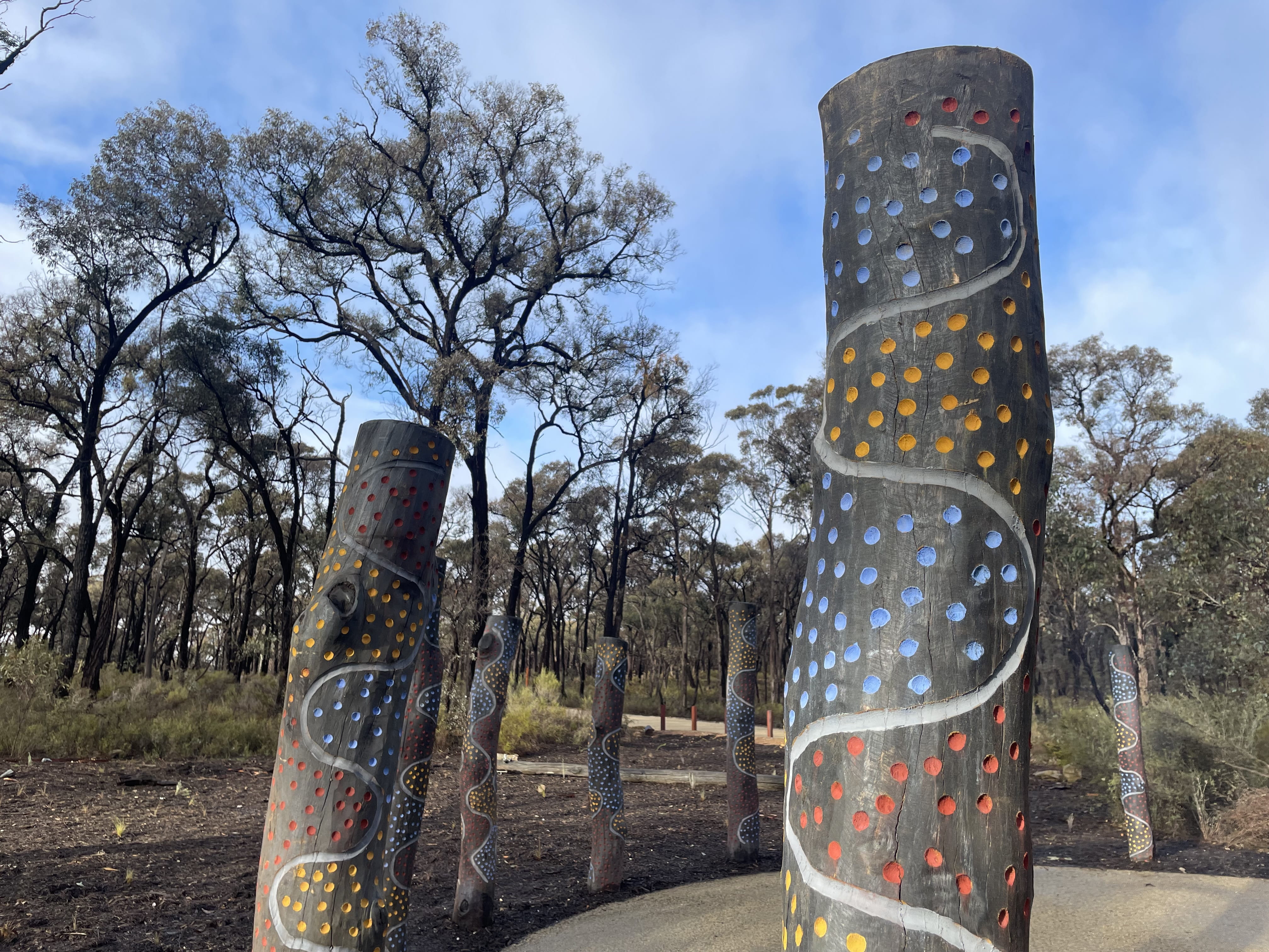 Poles painted with traditional artwork, with forest in background