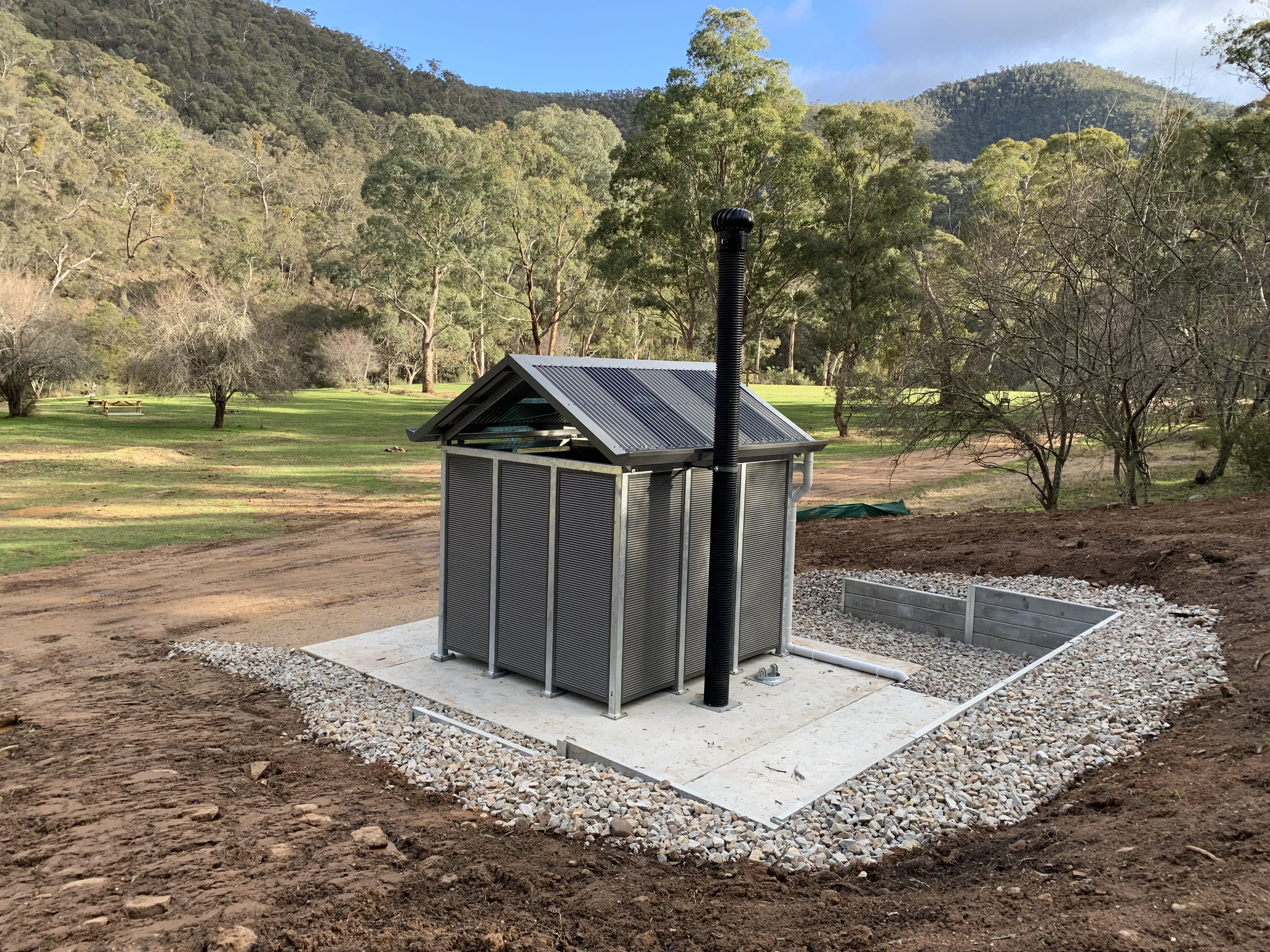 Newly constructed toilet with forested mountainside in background