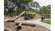 The new double storey tram fort in the all-abilities playscape at Wattle Park. It is yellow and green and has slides, steps, a path coming off it. 