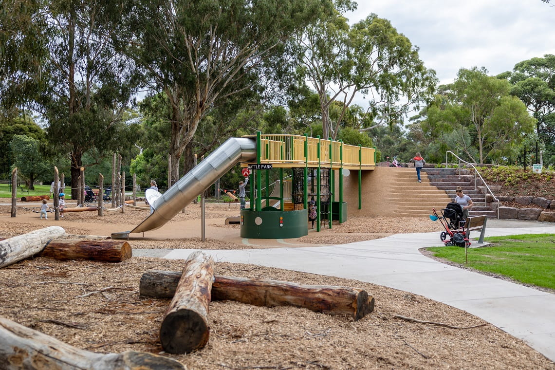 The new double storey tram fort in the all-abilities playscape at Wattle Park. It is yellow and green and has slides, steps, a path coming off it. 