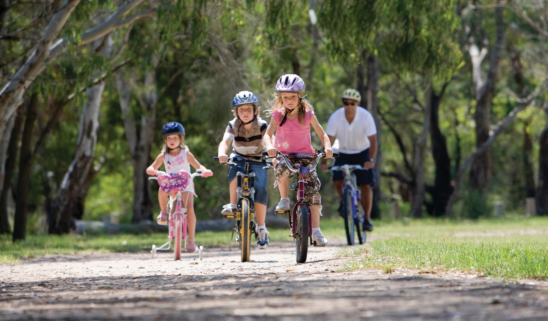 A family cycling on a path surrounded by trees