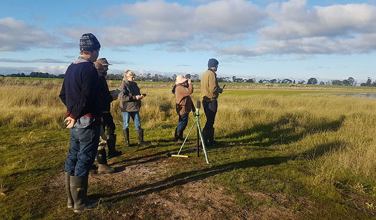 A group of people surveying the grassy landscape.