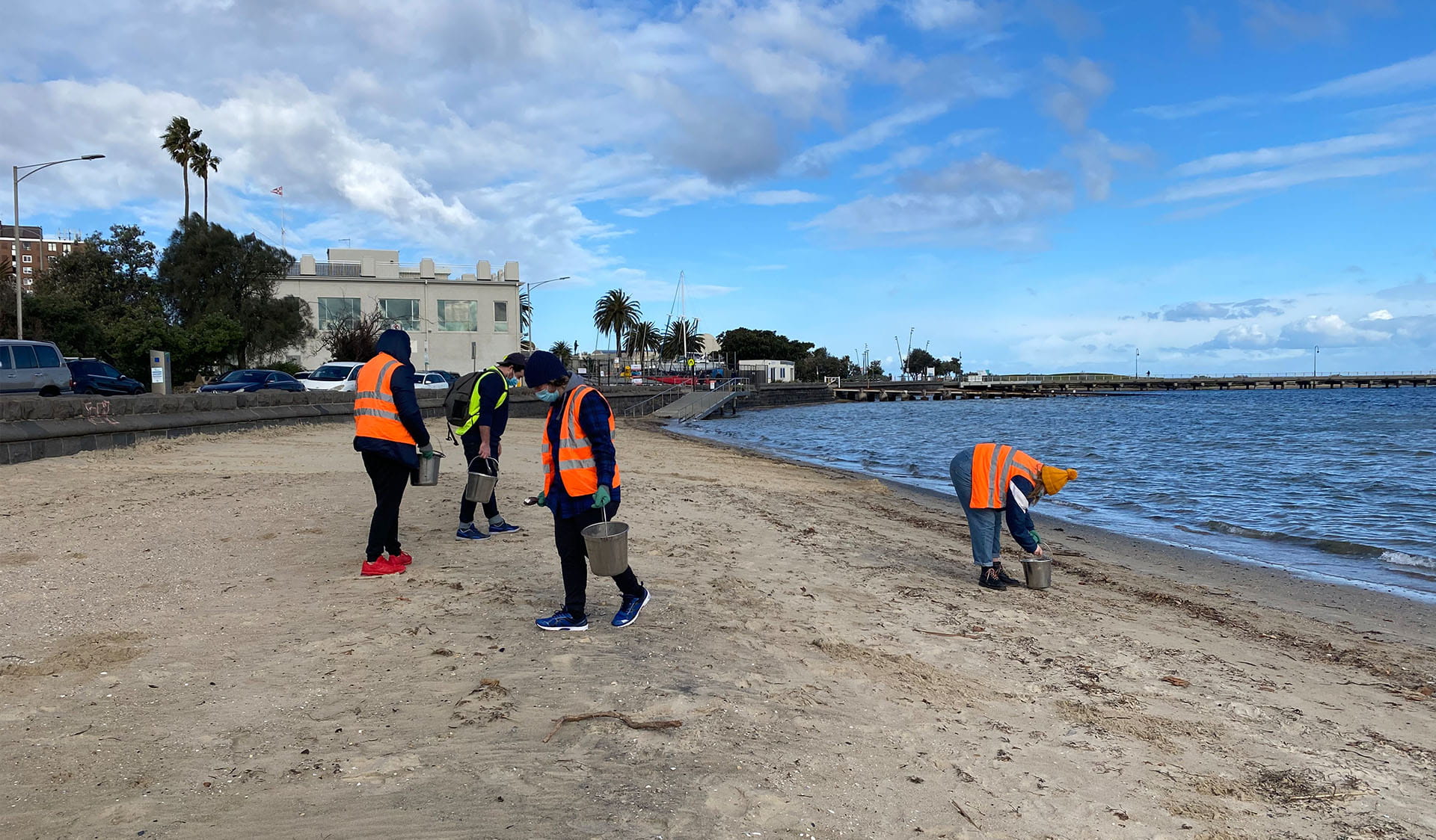 A group of volunteers in high vis vests meet on a beach