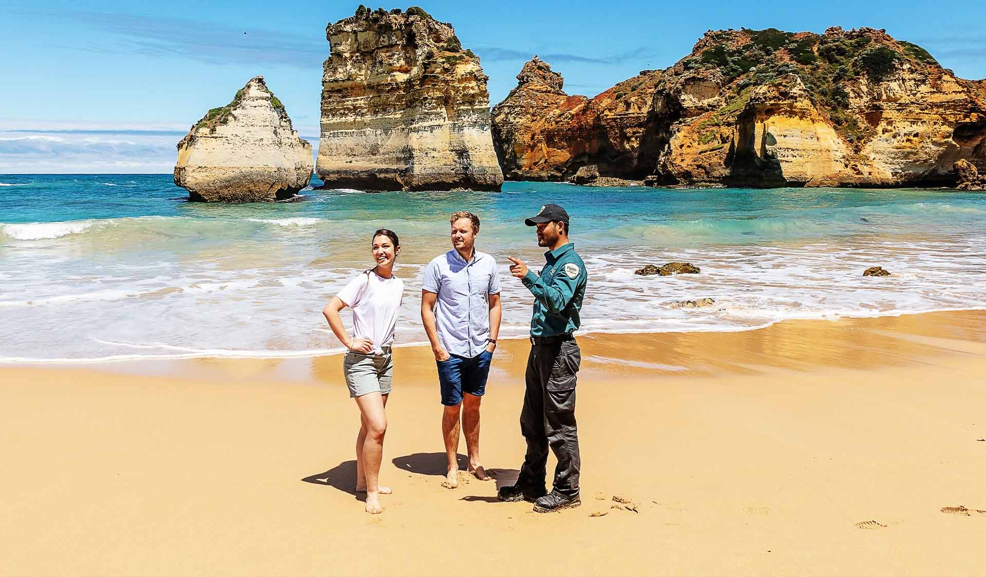 A ranger talks to two visitors on the beach at Port Campbell National Park