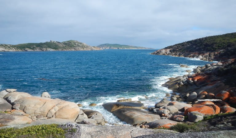 Ocean waves breaking onto rocks lining the rugged coastline.