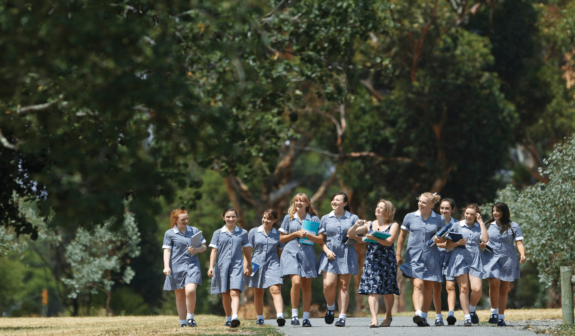 School students walking with teacher through an urban park on an excursion