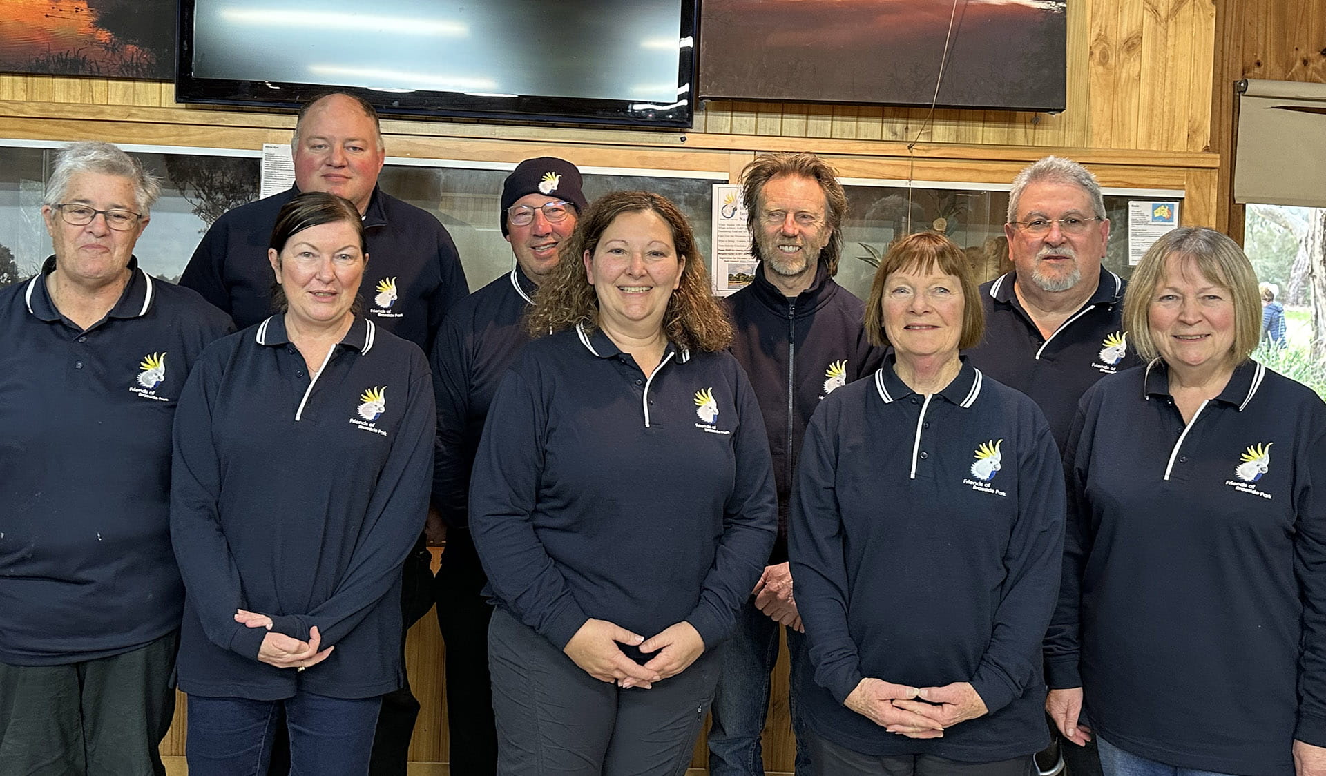 A group of volunteers dressed in uniforms smiling at camera.