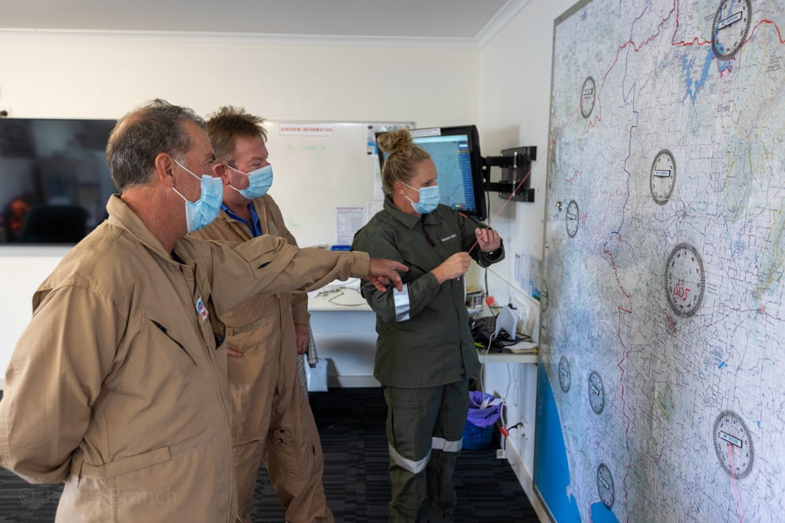 Rhianna and two of her colleagues consult a large map on the wall at the airbase