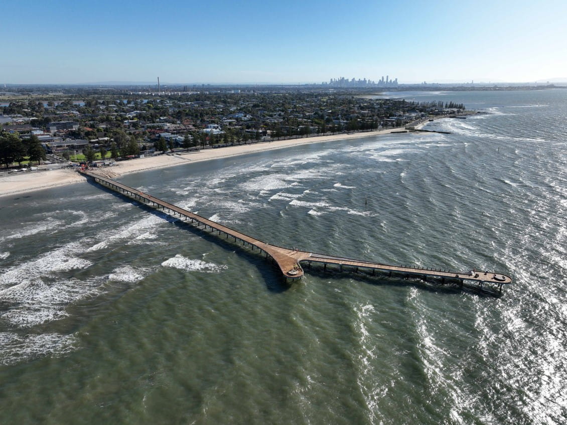 Aerial view of a long wooden pier with a branching end. 