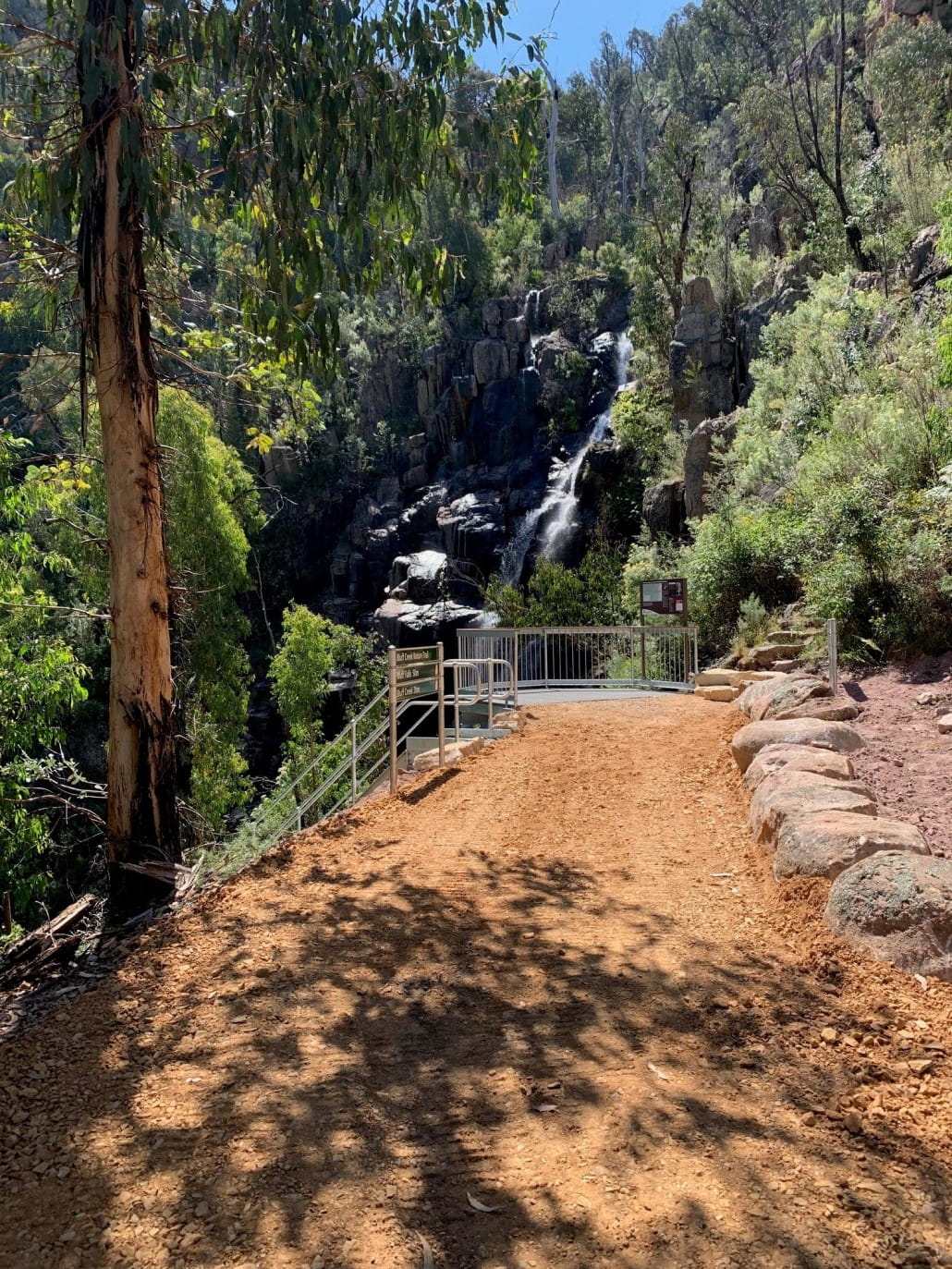 A waterfall among trees with a viewing platform in the foreground.
