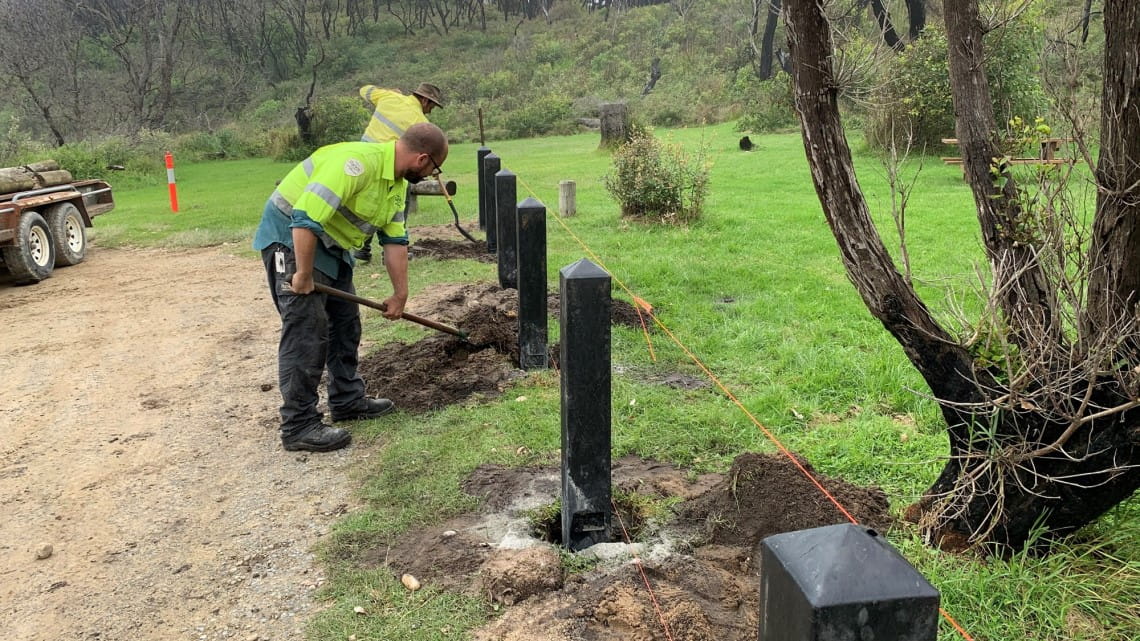 Two men digging holes for large bollards 
