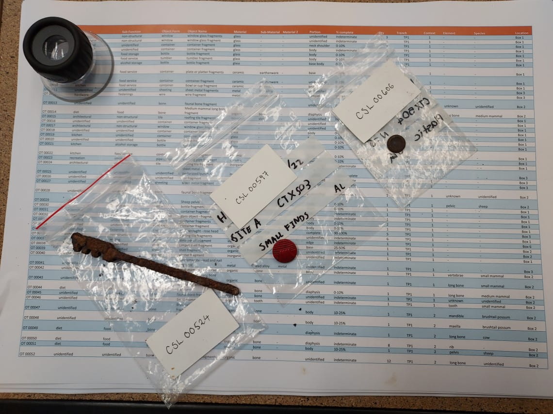 Two old buttons and a rusty pin in see-through bags on top of a table