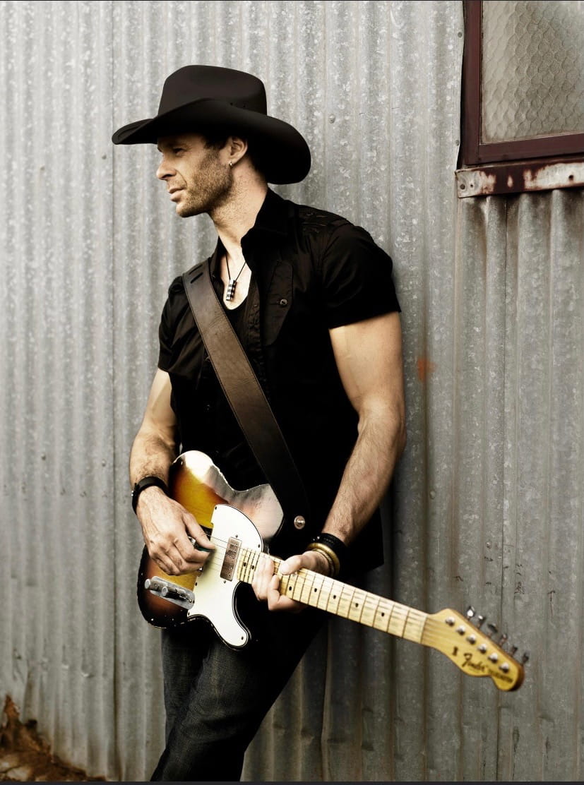 Lee Morgan looking away holding guitar