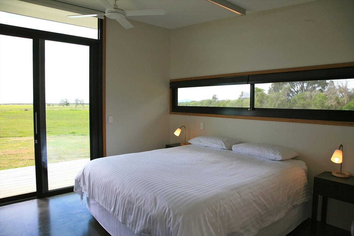 Inside view of bedroom with large window to the left of the room.