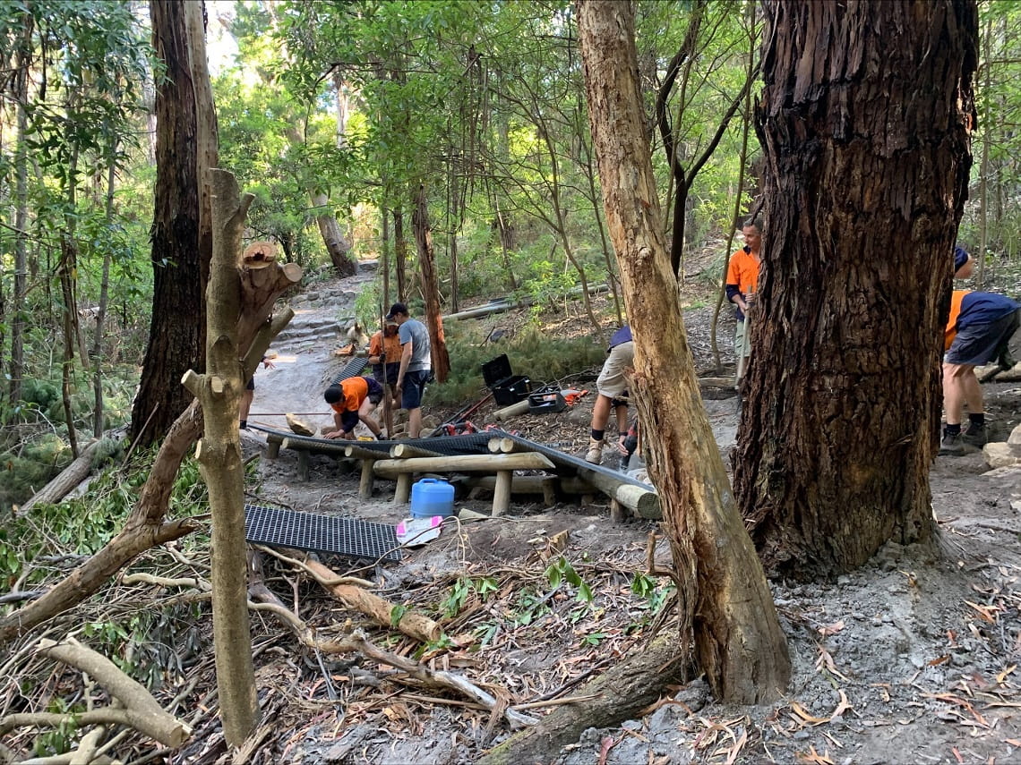 Teams wearing high visibility clothing repairing a mountain bike track