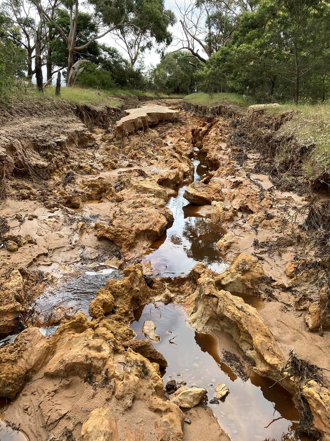 A damaged track where floodwaters have eroded the surface exposing the rocky craters beneath